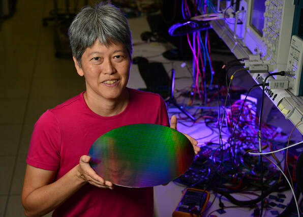 Woman holding a silicon wafer. Smiling.